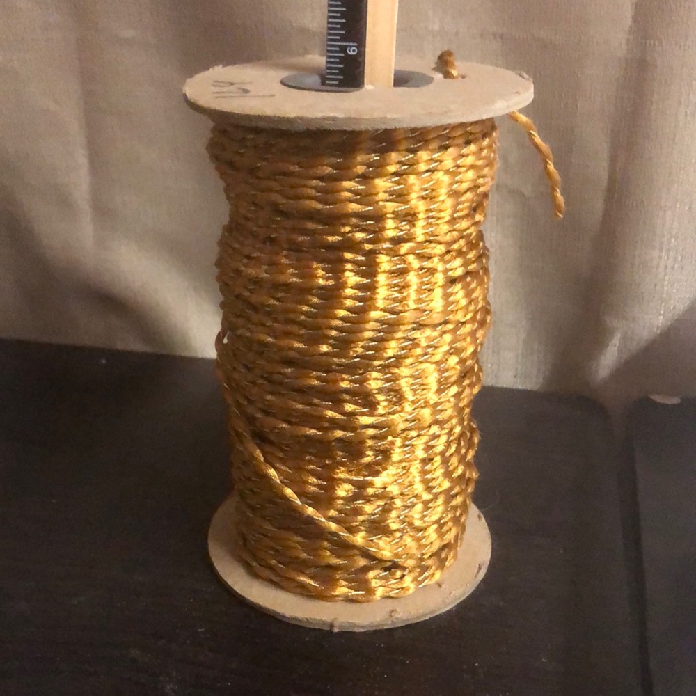 Twisted gold larger silky center with thin metallic shiny cord, entire spool.